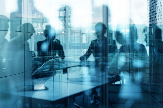 Reflection of people sat in an office on a glass window